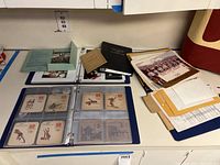 Overview of three-ring binders opened on a table showing plastic-sleeved pockets with Olympic-themed items