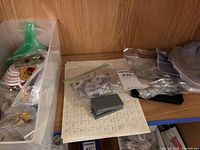 Plastic bin with multiple small bags of pins on wooden shelf