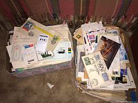 Two boxes filled with a variety of papers including postcards, receipts, and stamps, captured to show the overall lot contents.