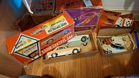 Overview of two toy cars, track guardrail pieces, Radio Control Car box, and Hot Wheels Race Set box