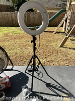 Full view of the GVM ring light mounted on the tripod stand outdoors, showing the ring light's round shape and tripod base.