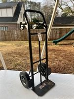 Front view of Milwaukee black hand truck showing two large rear wheels and front plate.