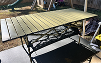 Full view of the aluminum slat top table outdoors on a sunny day showing the surface and foldable frame.
