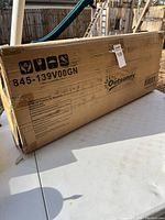 Box labeled with model number 845-139V00GN for Outsunny greenhouse, showing care and handling symbols and shipping label.