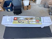 Ozark Trail instant canopy frame in gray carrying bag placed on black foldable table with garage background.