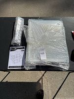 Metal panels and assembly components for PawHut kennel wrapped in bubble wrap, viewed on table.