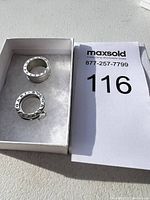 Two rings in white jewelry box with MaxSold lot card visible