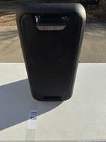 Front view of the black Sony GTK-XB5 Bluetooth speaker with front grille, carrying handle, and item number tag visible on white table outside.