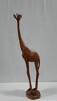 Full height view of the 49 inch carved wooden giraffe on a round base showing long neck and body markings.