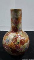 Full front view of the bulbous vase with colorful floral millefleur pattern and gold accents.