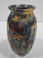 Front view of the vase showing dark blue and brown layered glaze with gold maple leaf decorations randomly placed around the body.