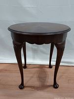 Front view of the round mahogany occasional table with curved legs and carved detail.