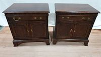 Front view of two matching mahogany bedside cabinets with drawer and double doors, brass hardware, and carved detailing
