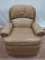 Full front view of the tan leather recliner chair showing armrests, seat, backrest and base.