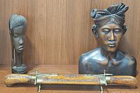 Wooden bust, tall carved head, cutlery scabbard on wooden surface