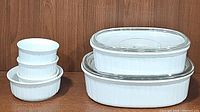 Photo showing set of 6 white CorningWare baking dishes; two large oval dishes with clear lids and four smaller round dishes without lids.