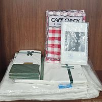 Photo of red and white square checked Cafe Check tablecloths and packaged white linen napkins and tablecloths.