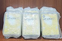 Three packages of GE soft white 60 watt light bulbs, wrapped in bubble wrap, stacked side by side.