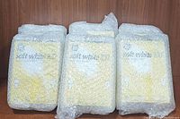 Six packages of GE soft white 100 watt light bulbs wrapped in bubble wrap in one image.