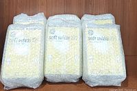 Three bubble-wrapped boxes of GE soft white 100 watt light bulbs, each box containing 4 bulbs, shown together.