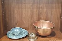 Antique molded metal pan, pewter bowl on pewter plate, copper pot on wooden shelf