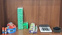 Photo of Scotch tape rolls with dispensers, stacked small tape packs, and large calculator and business card holder placed on wooden surface.