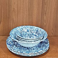 Stack of 3 blue floral pattern dinner plates with 3 side bowls stacked inside a large serving bowl all made of fine china.