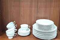 6 teacups stacked beside stacks of plates showing overall quantity and design details