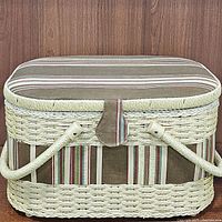 Closed view of woven sewing basket with striped fabric accents and double handles