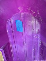 Close-up of the seating and interior of one purple sled showing wear, dirt, and a blue tag with the number 5.