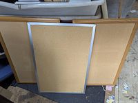 Three cork boards displayed side by side, two with wooden frames and one with a silver frame in front.