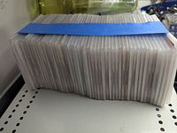 Stack of approximately 50 Redbox discs bundled with blue tape, showing the side edges of the individual discs in plastic sleeves.