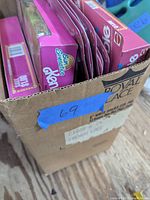 Box containing several Barbie fashion packs and doll boxes predominantly with pink packaging showing Sun Sensation Ken doll box end.