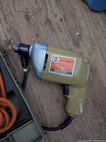 Side view of Black and Decker electric drill showing orange and black label and beige housing.