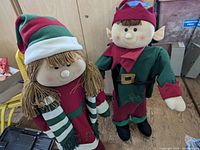Two approximately 3-foot tall Christmas greeter dolls, one boy and one girl, standing together shown from front