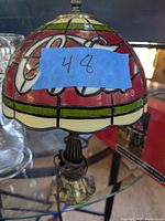 Photo showing stained glass style lamp shade with Coca-Cola logo and ornate base with cord.