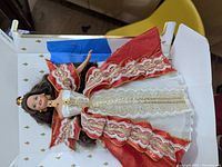 Barbie doll dressed in red and white elaborate gown with gold trim, out of box lying in packaging material