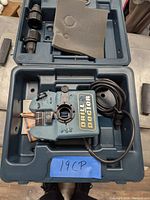 Blue plastic Drill Doctor sharpening unit inside blue plastic carrying case with attached power cord and adjustment lever visible on top.