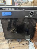 Front view of black Hotpoint built-in dishwasher showing the control dial and front panel.