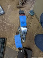 Top angled side view of chrome metal stands of two shaving mirrors with blue tape labels.