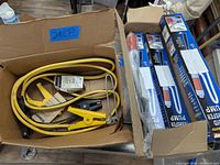 Box showing yellow jumper cables and three boxed liquid transfer pumps.