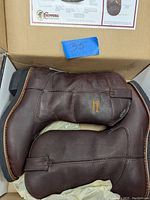 Pair of brown leather Chippewa waterproof work boots inside box with size indicator.