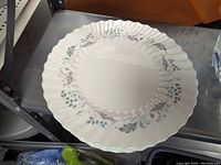 Close-up of individual dinner plate showing floral pattern and scalloped edge