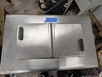 Top view of vintage ice cream freezer showing two hinged lids with black handles.