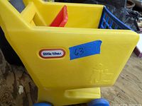 Side view showing the Little Tikes logo sticker, yellow plastic body, red interior divider, and blue plastic wheels.