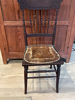 Full front view of the Victorian dining chair showing worn leather seat, carved backrest, and turned legs.