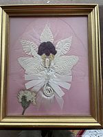 Frontal view of framed corsage showing entire arrangement with pink silk backing and gold frame.