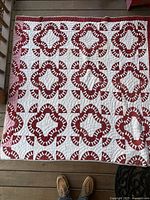 Full view of entire quilt showing repeating clover pattern in red and white, square approx. 48 inches.