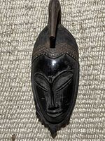 Front full view of the vintage wooden African mask showing carved facial details and headpiece