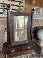 Full view of the early 1800s Empire period shaving mirror showing entire mirror, cylindrical column supports and drawer base.